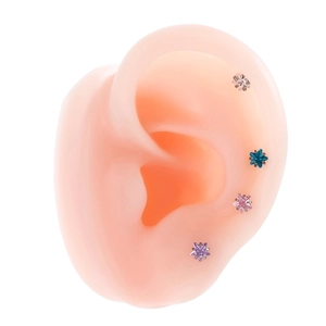 Star-shaped titanium steel ear studs with colorful zircon stones on a silicone ear model