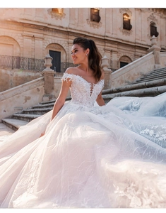 Detail of elegant off-shoulder lace wedding dress with cathedral train on grand stairs