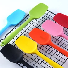 Detailed view of colorful large silicone spatulas arranged on a black grill rack