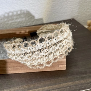 Close-up of hand-woven linen headband with natural beige hollow braided wave patterns
