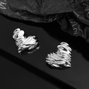 Macro shot of silver heart studs with unique wrinkled texture on a dark artistic background