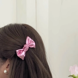 Pink metallic leather bow hair clip worn by model for an elegant sparkling look