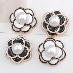 Detailed view of four camellia flower charms with pearl centers and gold edges