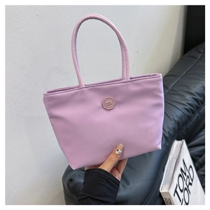 Détail d'un sac seau en nylon violet avec une boucle décorative ronde ornée de la lettre m