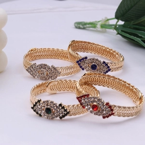 Vintage gold spiral woven bracelets with colorful crystal evil eye charms on white background