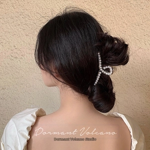Elegant gold pearl claw clip shown securing a sophisticated bun hairstyle
