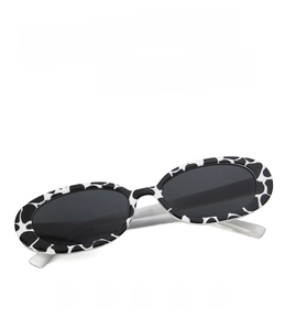 Detail view of oval cow print sunglasses frame with high-definition dark grey lenses