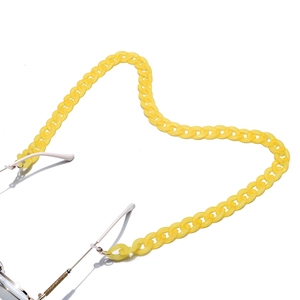 Detail of yellow acrylic eyeglass chain shaped into a heart on a white surface