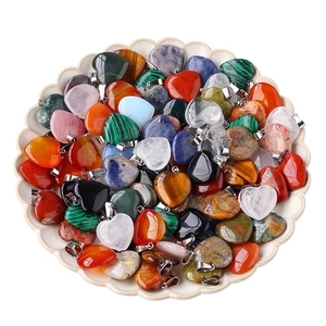 Assorted 20mm natural stone heart pendants in various crystals on a white ceramic dish