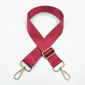 Close-up of adjustable wine red nylon bag strap with polished gold metal hardware