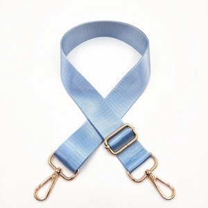 Close-up of light blue nylon bag strap with polished gold metal buckles and hooks