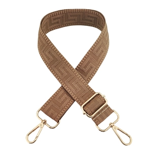 Detail of adjustable woven bag strap with brown geometric pattern and gold metal hooks