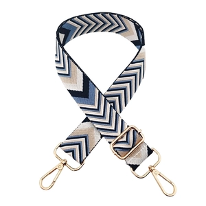 Close-up of geometric wave pattern woven bag strap with golden metal lobster clasps