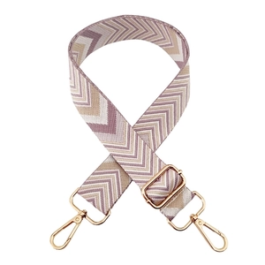 Detail of adjustable wide woven bag strap with colorful chevron pattern and gold metal hooks