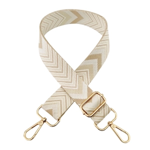 Detail of adjustable woven bag strap with beige chevron pattern and gold metal hardware