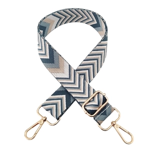 Detail of adjustable woven wide bag strap with arrow pattern and gold metal buckles