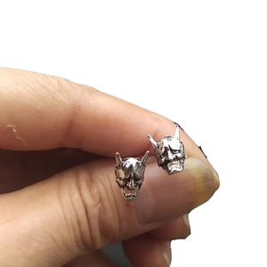 Vintage silver punk style Japanese Hannya mask stud earrings held between fingers