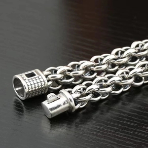 Bracciale da uomo a catena con croce d'argento e trama intrecciata su fondo in legno scuro