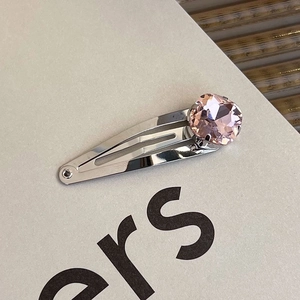 Macro detail of silver metal hair clip featuring a large faceted pink heart crystal