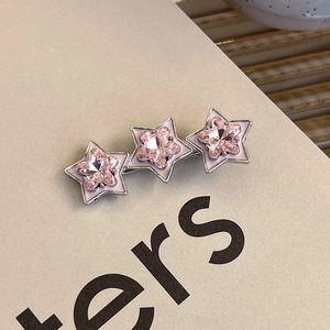 Close-up of stars hair clip with pink heart-shaped crystals and white enamel on silver base