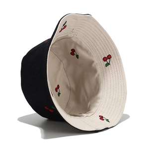 Detailed close-up of reversible bucket hat with red cherry embroidery on black cotton fabric