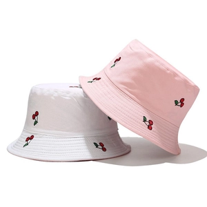 Detail of white and pink reversible cotton bucket hats with red cherry embroidery