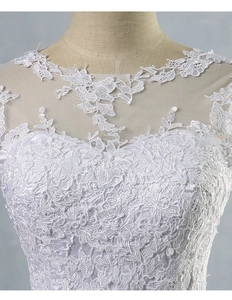 Dettaglio dell'intricato ricamo floreale e dello scollo trasparente su un abito da sposa