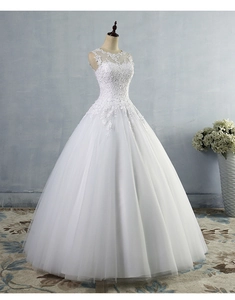 Dettaglio dell'abito da sposa bianco in pizzo con ricami floreali e scollo trasparente