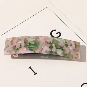 Détail de la pince à cheveux en acétate marbré rose et vert avec ressort métallique