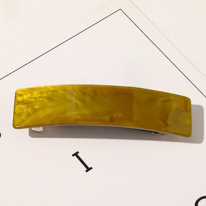 Vue détaillée d'une pince à cheveux carrée en acétate avec motif marbré jaune et olive