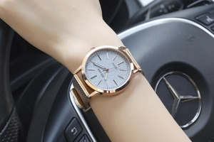 Luxury rose gold mesh watch with starry grey dial shown on wrist in car interior