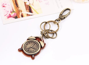 Detail of vintage bronze alarm clock keychain with brown leather base and metal clasp