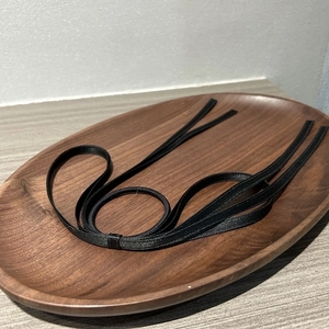 Elegant black satin ribbon hair tie with bow design on a minimalist wooden tray