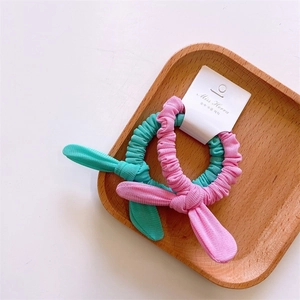 Detail of mint green and pink rabbit ear scrunchies with ribbed texture in a wooden tray