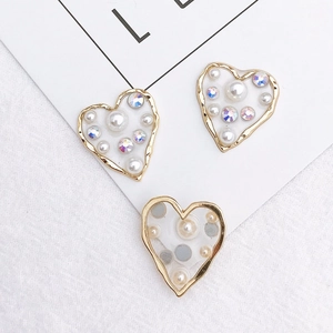 Macro view of heart-shaped DIY charms with white pearls and sparkling rhinestones