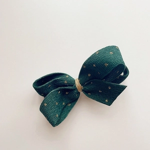 Detail of dark green corduroy hair clip with gold glitter polka dots and knot detail