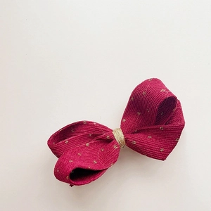 Detailed view of pink corduroy hair clip with gold dots and layered 3D bow design