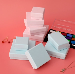Pink and light blue jewelry gift boxes in various sizes displayed on a warm pink background