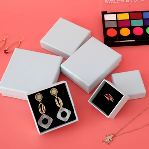 Minimalist white jewelry gift box set with black foam inserts on a pink background