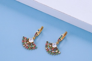Macro shot of fan-shaped gold earrings with multicolored zircon pavé and a center crystal