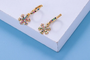 Macro detail of golden snowflake hoop earrings with multicolored cubic zirconia crystals