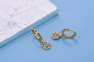 Detail of gold hoop earrings with hexagonal pendants featuring multi-color zircon stones