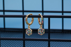 Detail of gold hoop earrings with hexagonal pendants featuring multi-colored micro-pave zircons