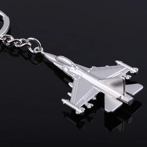 Macro shot of silver metal fighter jet keychain showing realistic wing details and finish