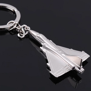 Close-up of a silver fighter jet keychain showing metallic details on black background