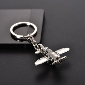 Macro shot of silver propeller aircraft keychain with polished metal finish on dark surface