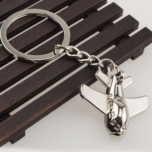 Close-up of a silver fighter jet metal keychain on a dark wooden background