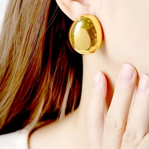 Elegant gold oval bean stud earrings with a minimalist polished metallic finish on a model