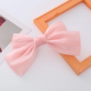 Macro detail of a pink pearlescent satin bow hair clip with double-layer pleated texture