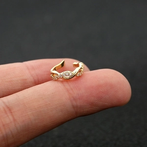 Macro shot of gold-plated non-pierced ear cuff with sparkling zircon cross-twisted design